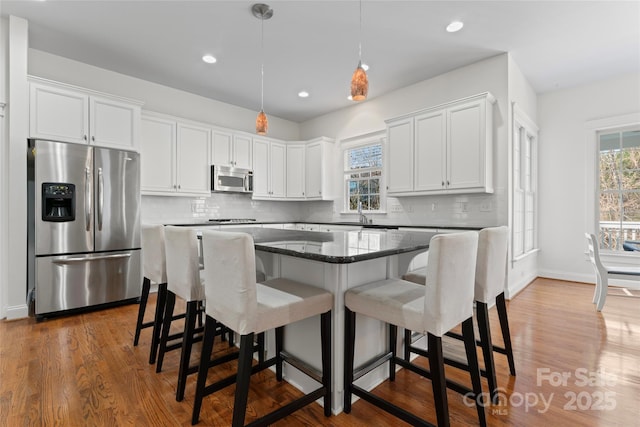 kitchen with tasteful backsplash, appliances with stainless steel finishes, and white cabinets