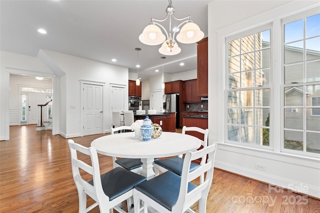 dining area with recessed lighting, a notable chandelier, light wood-style floors, stairs, and a healthy amount of sunlight