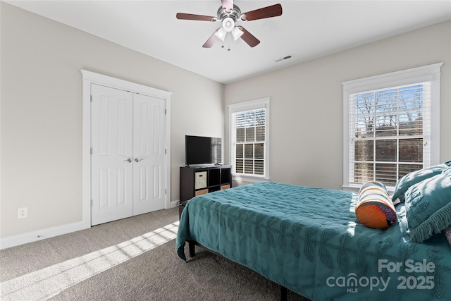 carpeted bedroom with a ceiling fan, a closet, visible vents, and baseboards