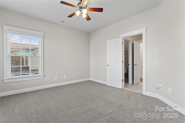 spare room with light carpet, ceiling fan, visible vents, and baseboards