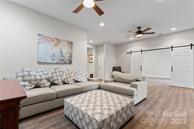 living area with a barn door, a ceiling fan, wood finished floors, and recessed lighting