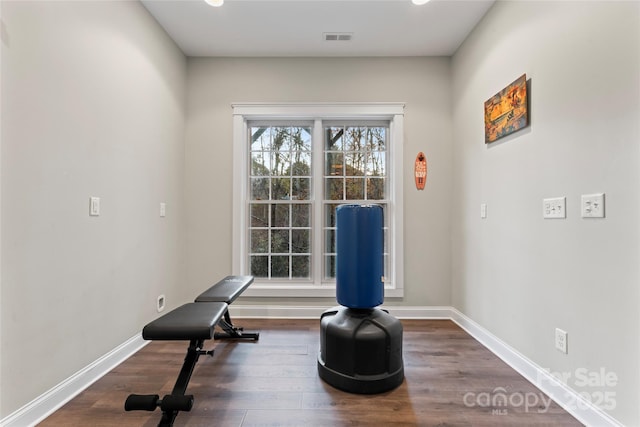 workout room with baseboards, visible vents, and wood finished floors