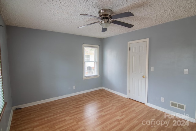 empty room featuring a textured ceiling, light hardwood / wood-style floors, and ceiling fan