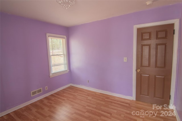 spare room featuring a chandelier and light hardwood / wood-style floors