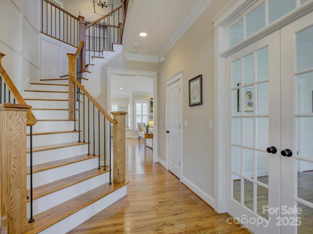 entrance foyer with crown molding, light hardwood / wood-style flooring, and french doors