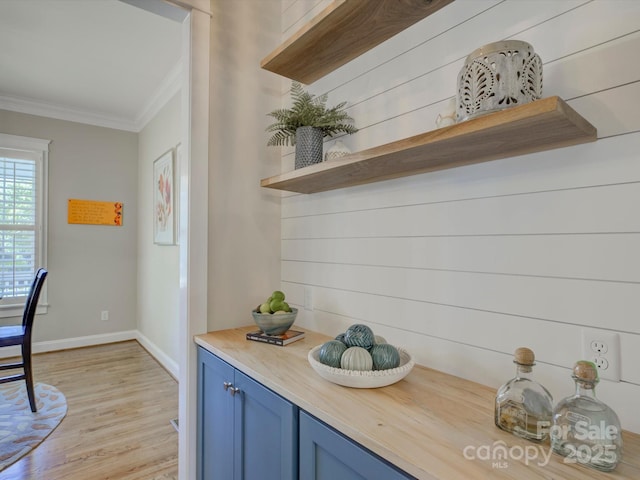 kitchen featuring light wood-type flooring, ornamental molding, and blue cabinetry