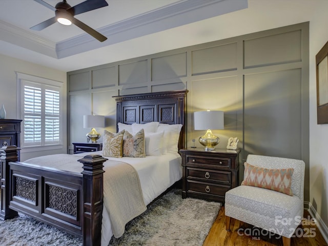 bedroom featuring ornamental molding, hardwood / wood-style floors, ceiling fan, and a tray ceiling