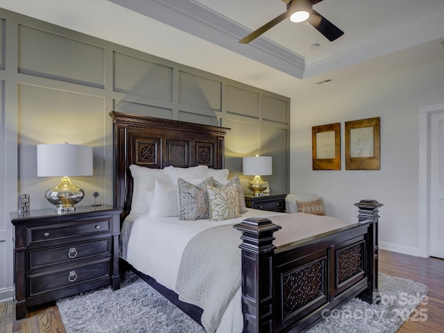 bedroom with ceiling fan, ornamental molding, a raised ceiling, and hardwood / wood-style floors