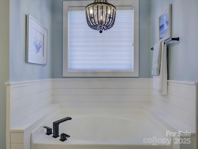 bathroom featuring an inviting chandelier and a bathing tub