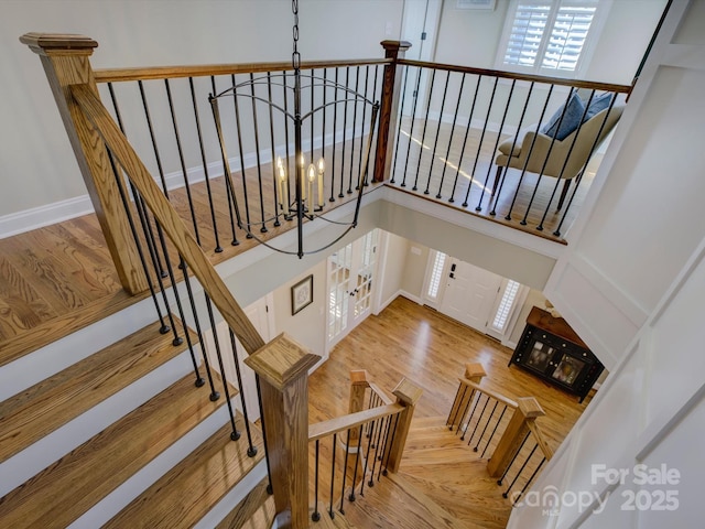 staircase featuring hardwood / wood-style floors, a chandelier, and a high ceiling