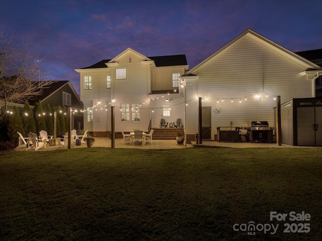 back house at dusk with a yard, a fire pit, a patio, and a storage unit