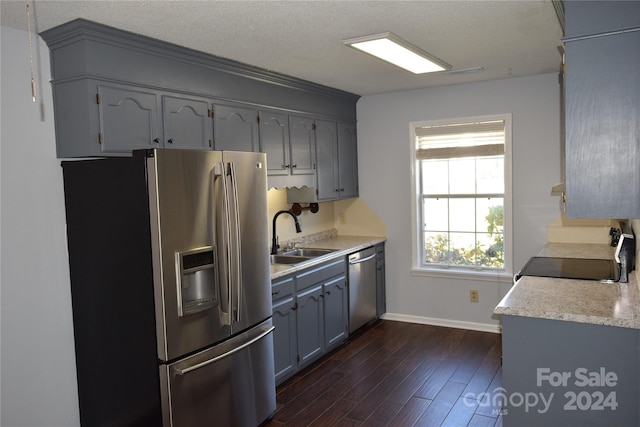 kitchen featuring sink, dark hardwood / wood-style flooring, a textured ceiling, gray cabinets, and appliances with stainless steel finishes