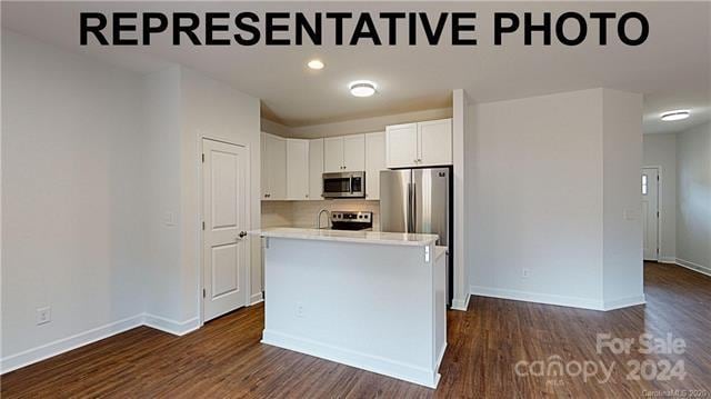 kitchen featuring appliances with stainless steel finishes, backsplash, a kitchen island, dark hardwood / wood-style floors, and white cabinetry