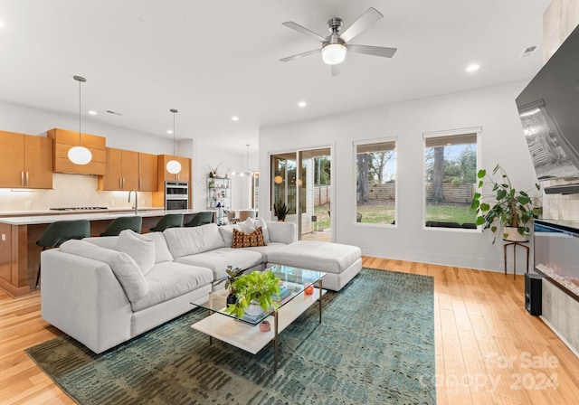 living room featuring ceiling fan, light wood-type flooring, and sink