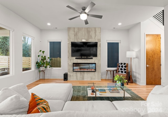 living room featuring hardwood / wood-style flooring, ceiling fan, and a fireplace