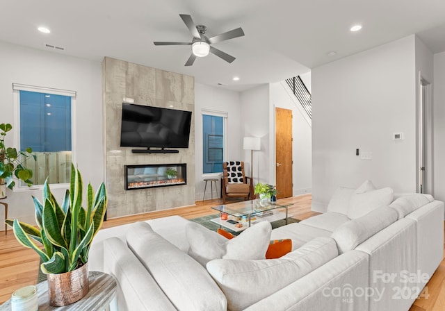 living room with ceiling fan, a fireplace, and hardwood / wood-style flooring