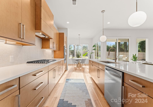 kitchen featuring decorative light fixtures, stainless steel appliances, light hardwood / wood-style flooring, and sink