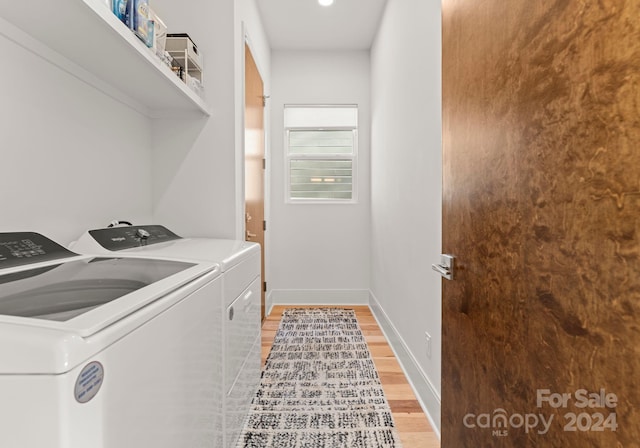 clothes washing area featuring washing machine and dryer and light hardwood / wood-style flooring