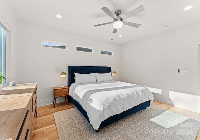 bedroom with ceiling fan, light wood-type flooring, and multiple windows