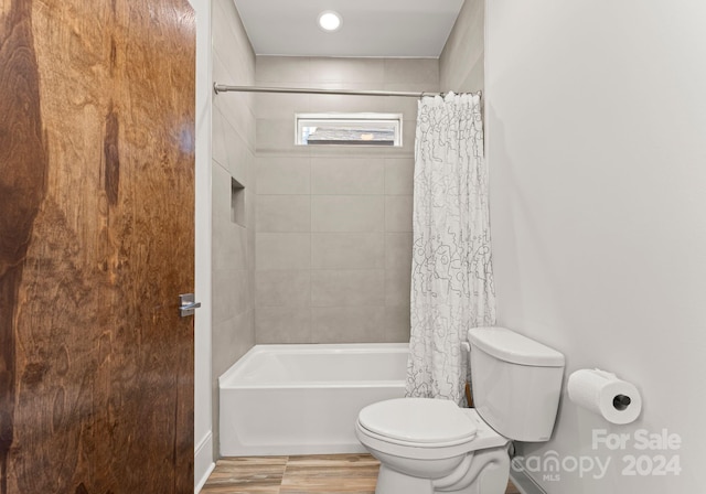 bathroom with hardwood / wood-style flooring, shower / bath combination with curtain, and toilet