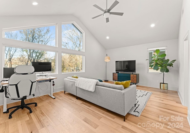 living room with light hardwood / wood-style floors, high vaulted ceiling, and ceiling fan