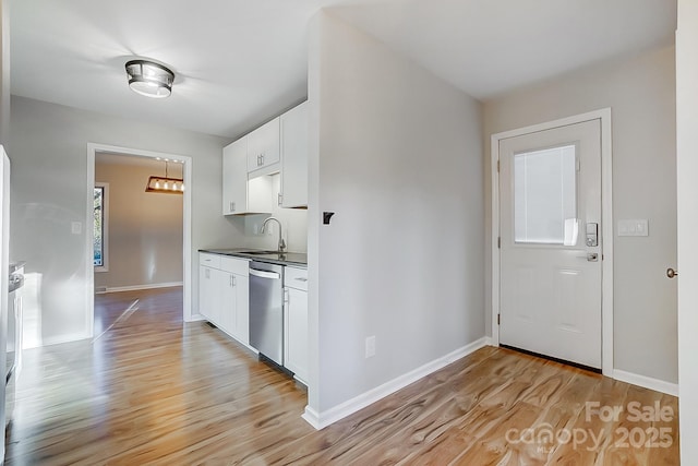 kitchen with white cabinets, light hardwood / wood-style floors, stainless steel dishwasher, and sink