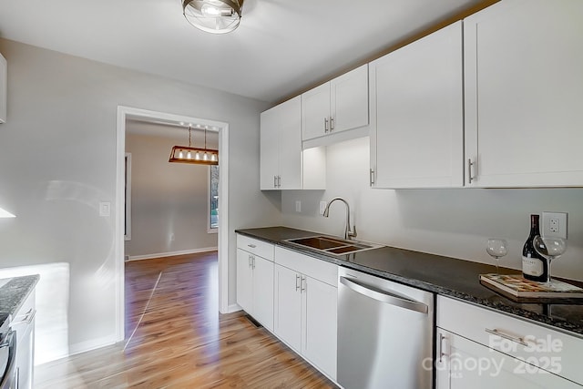 kitchen featuring dark stone counters, sink, stainless steel dishwasher, light hardwood / wood-style floors, and white cabinetry