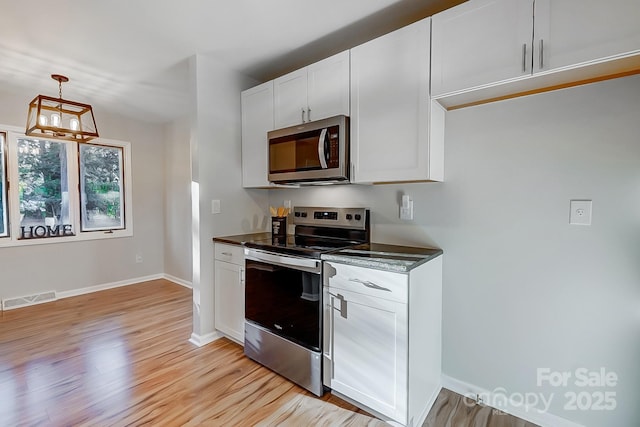 kitchen with white cabinets, decorative light fixtures, stainless steel appliances, and light hardwood / wood-style flooring