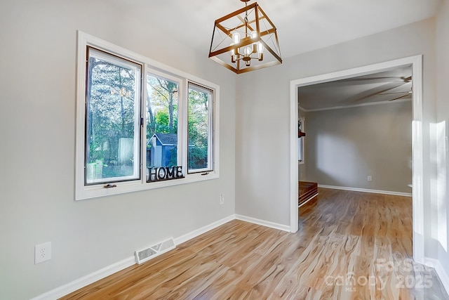 unfurnished room featuring ceiling fan with notable chandelier and light hardwood / wood-style flooring