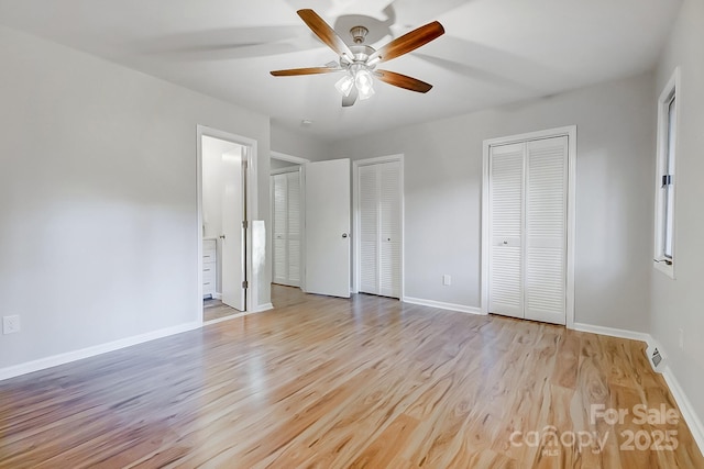 unfurnished bedroom with ceiling fan, two closets, and light wood-type flooring