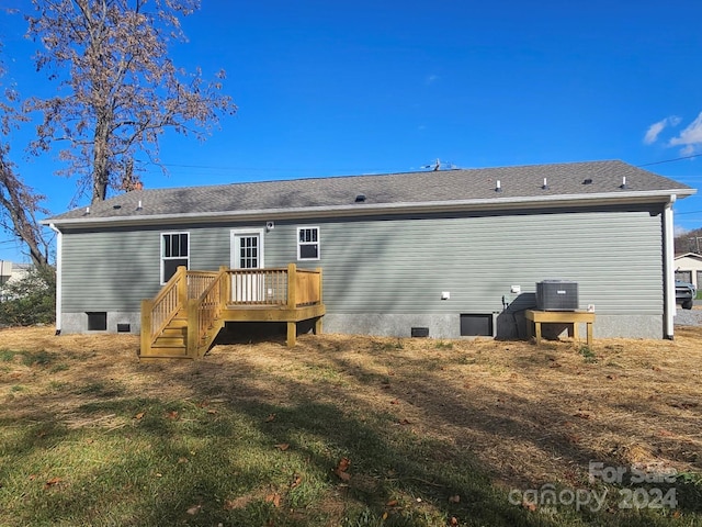 rear view of house featuring a lawn, a wooden deck, and central air condition unit