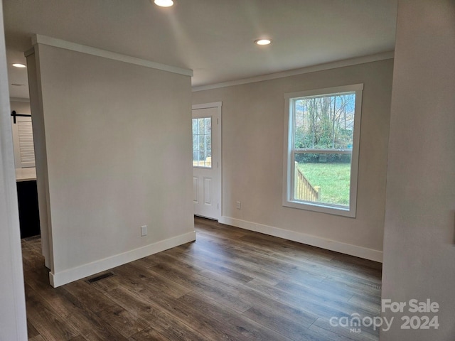 spare room featuring crown molding and dark wood-type flooring