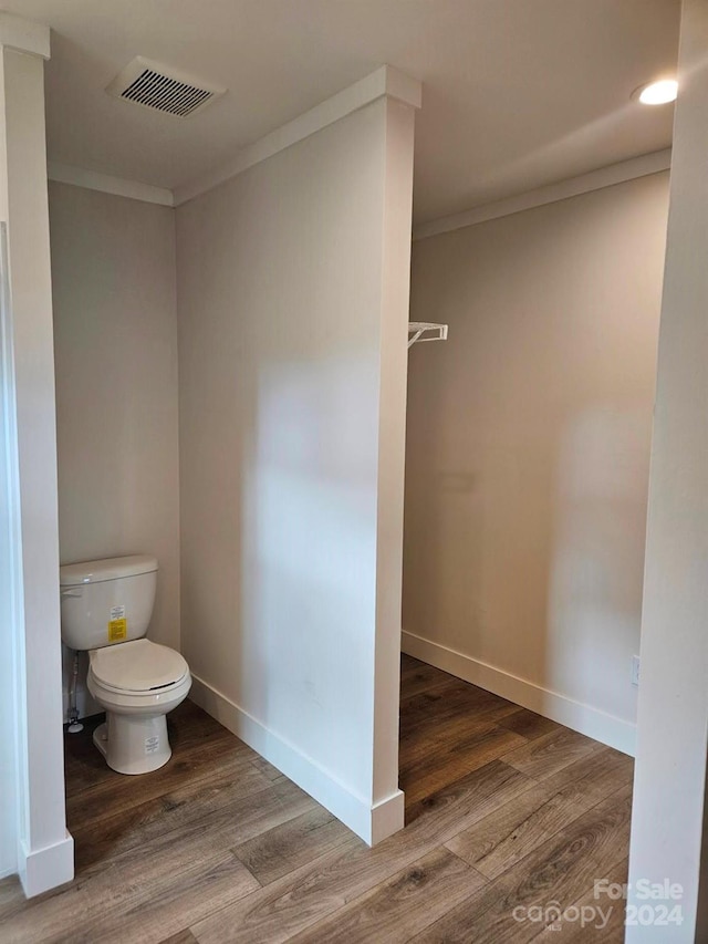 bathroom featuring hardwood / wood-style floors, toilet, and ornamental molding