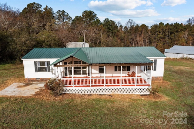 rear view of house with covered porch and a yard