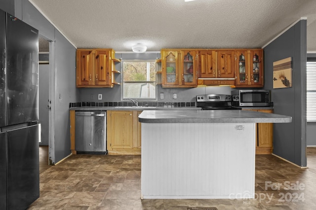 kitchen with a textured ceiling, a kitchen island, sink, and stainless steel appliances