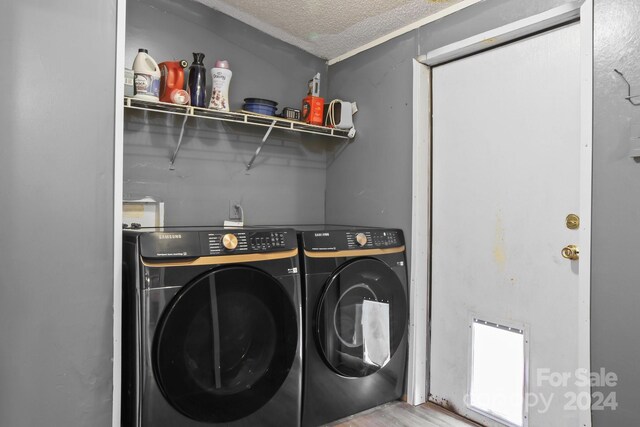 clothes washing area featuring washing machine and dryer, a textured ceiling, and light hardwood / wood-style flooring