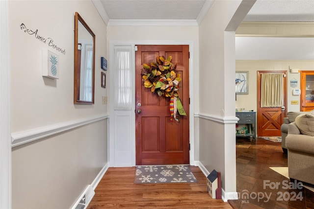 foyer featuring hardwood / wood-style floors, a textured ceiling, and crown molding