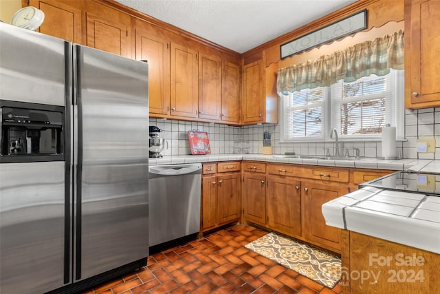 kitchen featuring tile counters, sink, appliances with stainless steel finishes, and tasteful backsplash