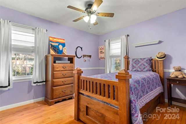 bedroom featuring ceiling fan, a textured ceiling, and light wood-type flooring