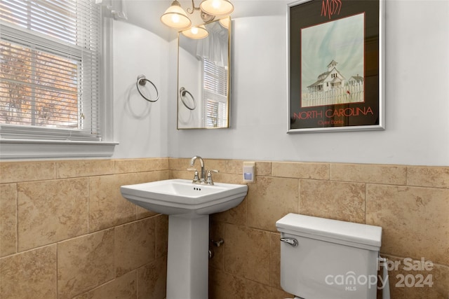 bathroom featuring sink, tile walls, and toilet