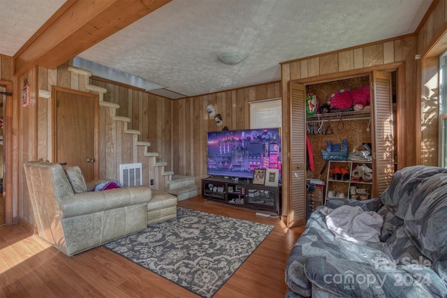 living room featuring wood-type flooring, a textured ceiling, and wooden walls