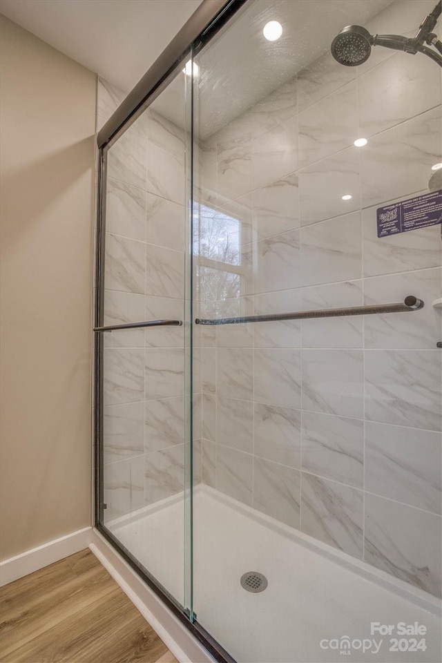 bathroom with hardwood / wood-style flooring and a shower with shower door