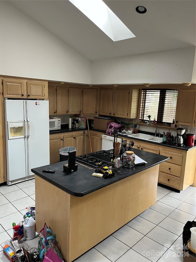 kitchen with white appliances, a skylight, a kitchen island, and sink