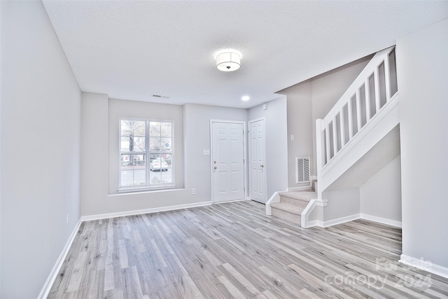 entrance foyer with a textured ceiling and light hardwood / wood-style flooring