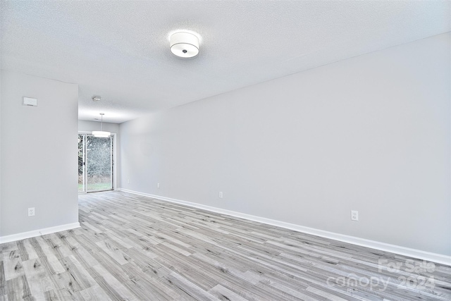 spare room with a textured ceiling and light wood-type flooring