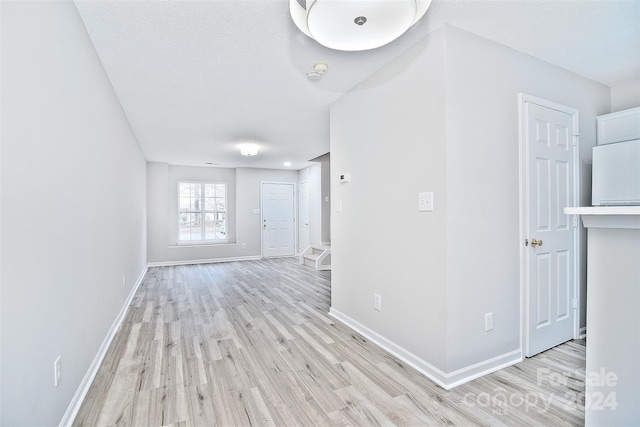 unfurnished room with light hardwood / wood-style flooring and a textured ceiling