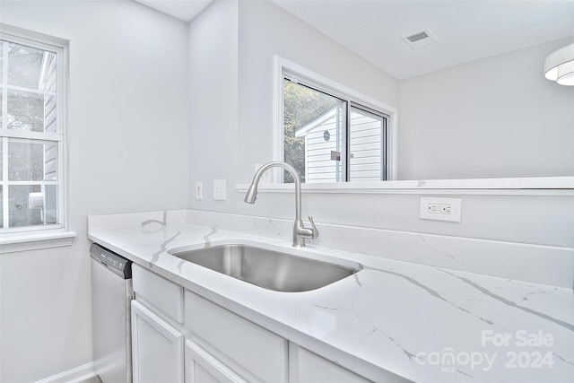 kitchen featuring light stone counters, stainless steel dishwasher, a textured ceiling, sink, and white cabinets