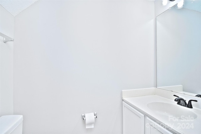 bathroom featuring vanity, a textured ceiling, and toilet