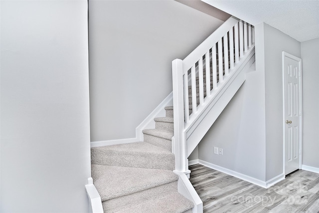 stairs featuring hardwood / wood-style floors and a textured ceiling