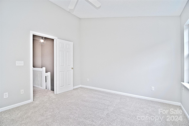 carpeted spare room with ceiling fan and lofted ceiling